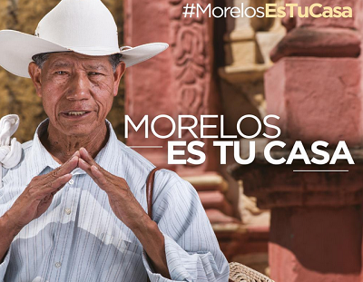 hombre vestido con camisa y sobrero junta las manos como simulando el techo de una casa